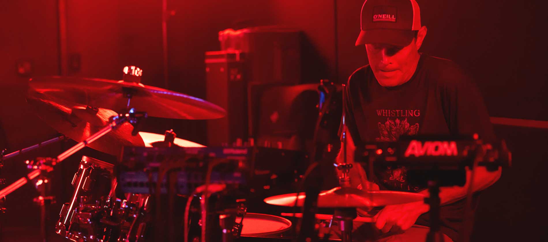 Drummer playing under red stage light