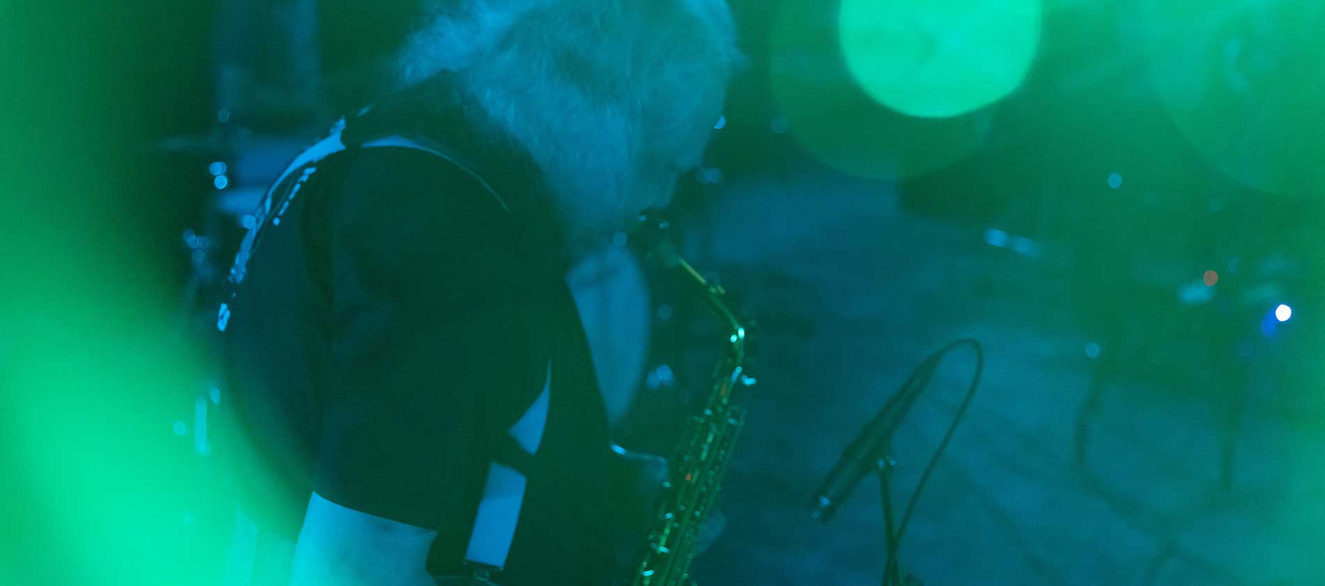 Saxophonist playing under green and blue stage light