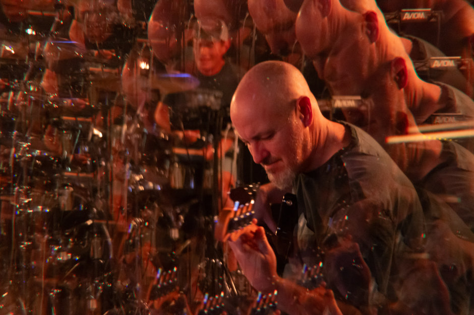 Bassist playing in warm orange light, multiplied by a prism effect