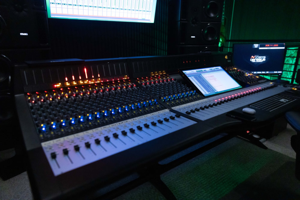 Mixing console and screens in the Lulu Studio control room, lit in green
