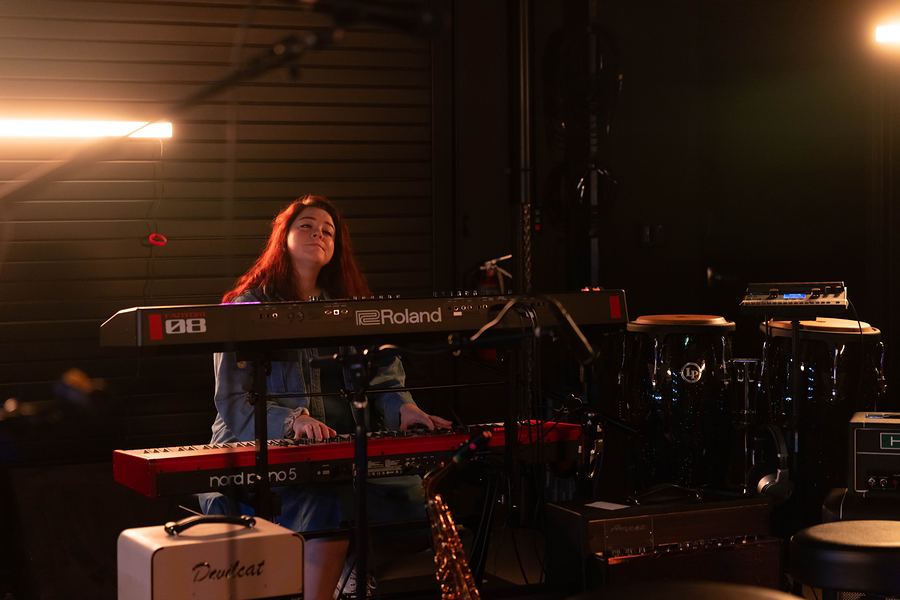 Singer playing a red Nord keyboard in the rehearsal room