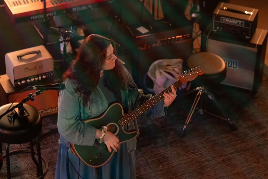 Overhead view of a singer playing acoustic guitar beside vintage amplifiers