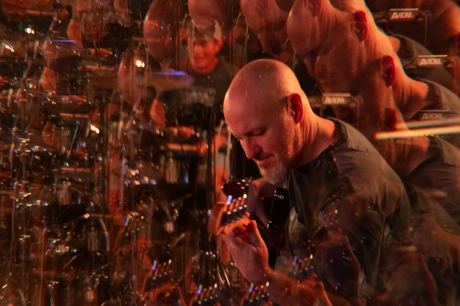 Bassist playing in warm orange light, multiplied by a prism effect
