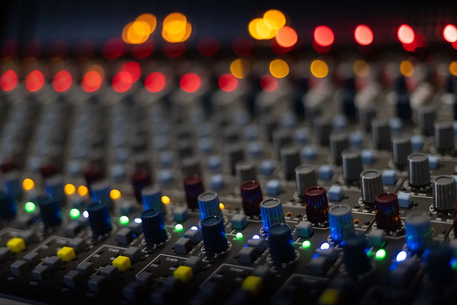 Close-up of mixing console knobs with colorful out-of-focus lights