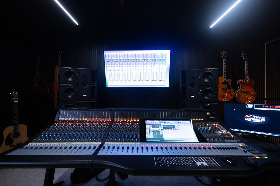Lulu Studio control room with a large mixing console, studio monitors and guitars on the wall