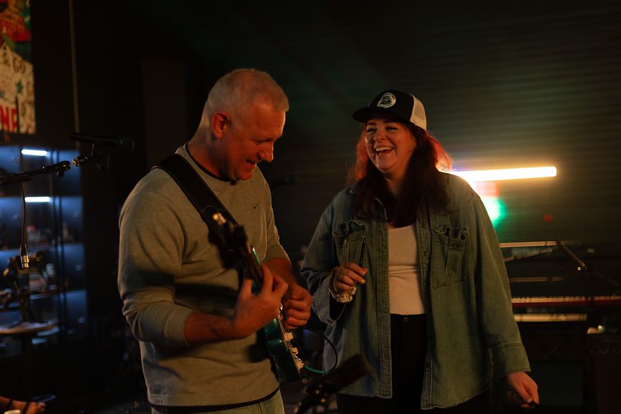 Guitarist and singer laughing together during rehearsal