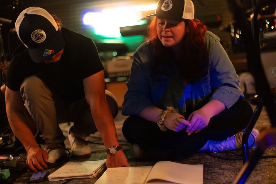 Two band members sitting on the floor going over notebooks of lyrics
