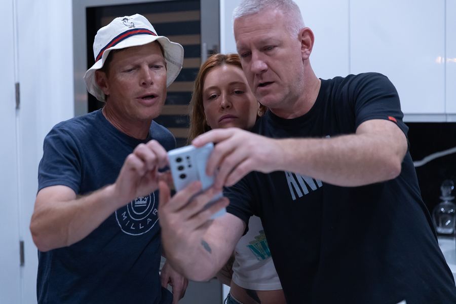 Three band members crowding around a phone screen