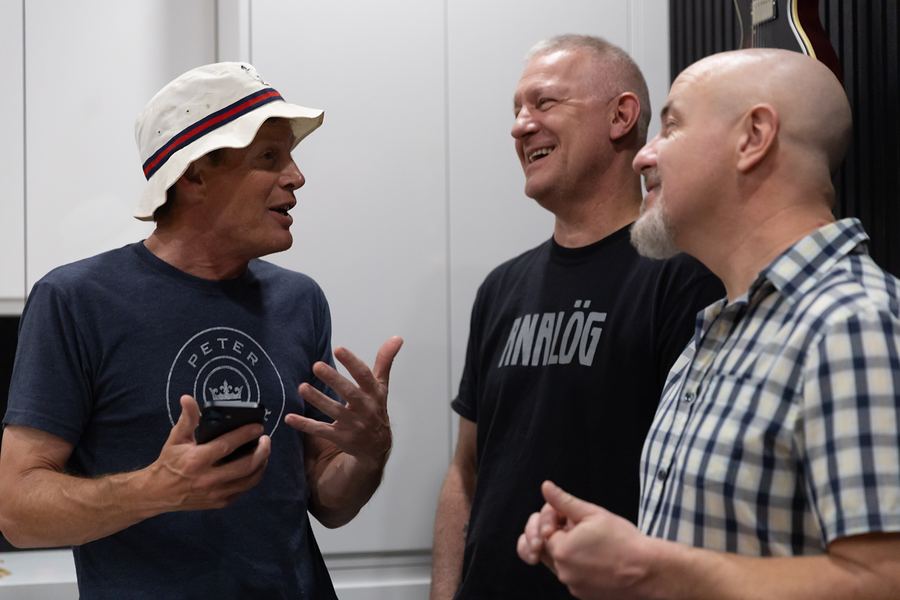 Three band members laughing together in the studio kitchen