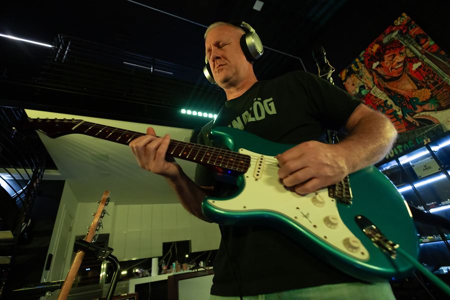 Low-angle shot of a guitarist in headphones playing a green Stratocaster