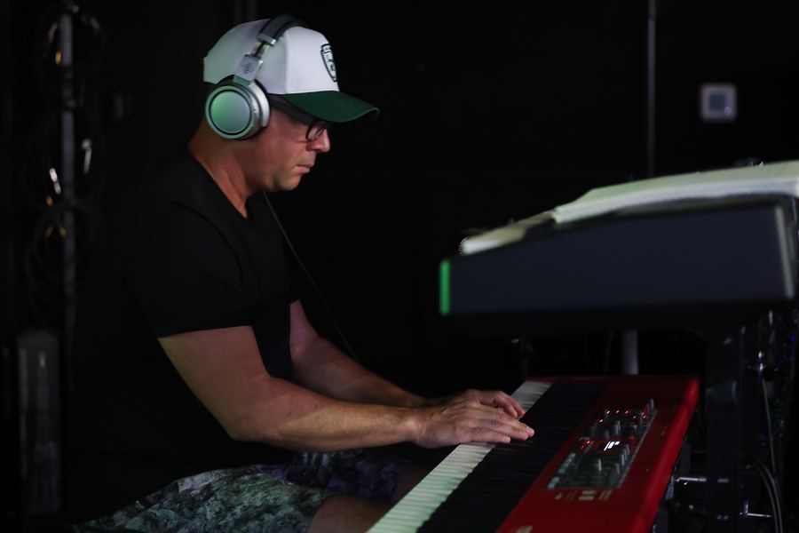 Keyboardist in headphones and a cap playing a red Nord keyboard